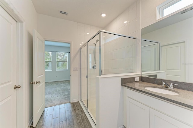 bathroom with visible vents, vanity, and a shower stall