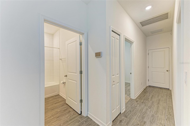 corridor with recessed lighting, light wood-type flooring, baseboards, and visible vents