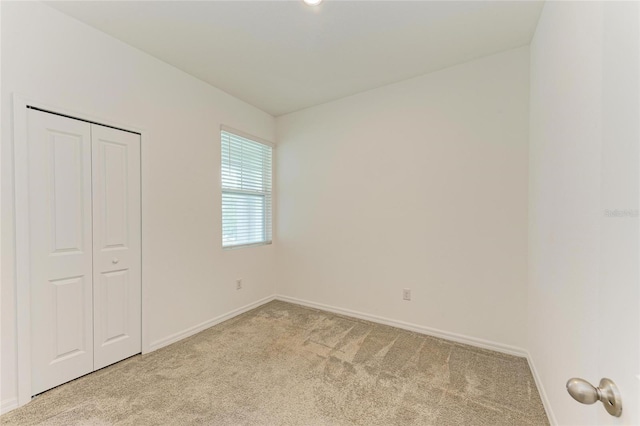 unfurnished bedroom featuring baseboards, a closet, and light carpet