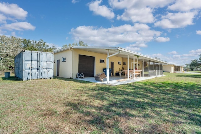 rear view of property with a garage, a patio area, and a lawn