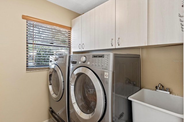 clothes washing area with independent washer and dryer, cabinets, and sink