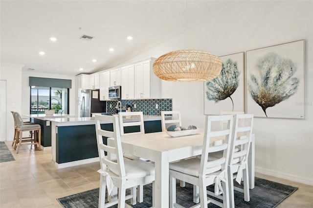 kitchen with lofted ceiling, appliances with stainless steel finishes, backsplash, white cabinets, and decorative light fixtures