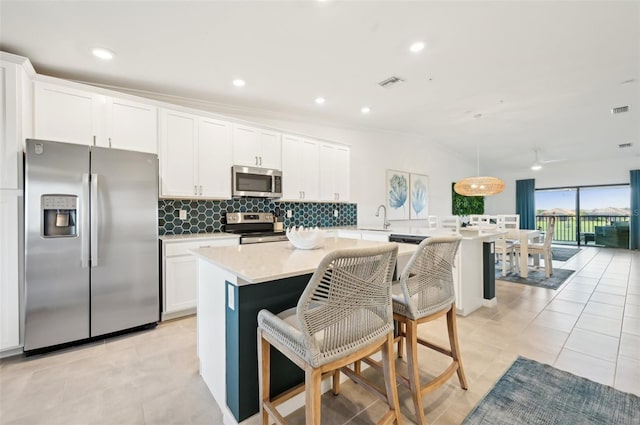 kitchen with white cabinetry, a breakfast bar, an island with sink, and appliances with stainless steel finishes