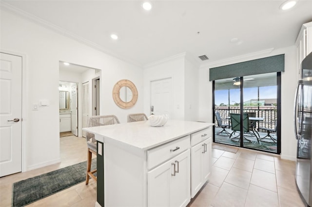 kitchen with white cabinetry, crown molding, a center island, stainless steel refrigerator, and ceiling fan