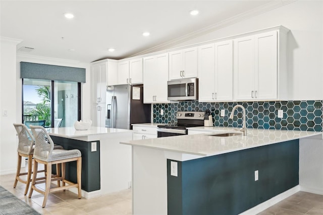 kitchen with sink, a breakfast bar area, white cabinets, kitchen peninsula, and stainless steel appliances