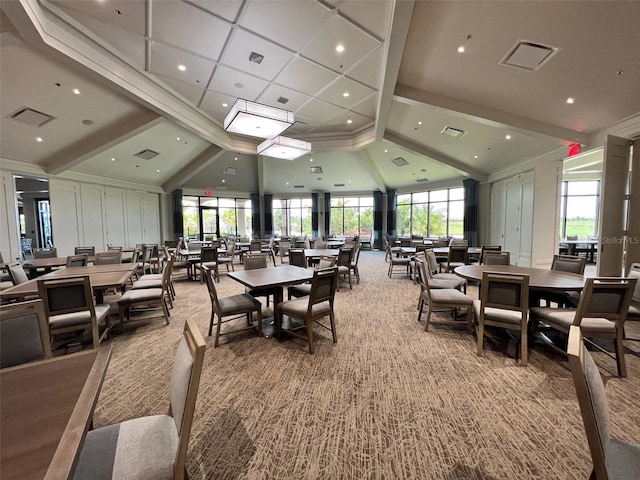 carpeted dining space with a towering ceiling and beamed ceiling