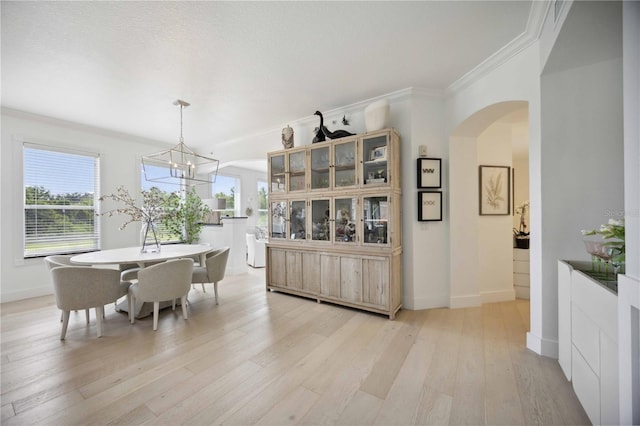 dining room featuring crown molding, light hardwood / wood-style floors, a chandelier, and a textured ceiling