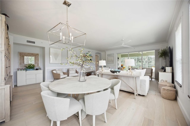 dining area with crown molding, plenty of natural light, an inviting chandelier, and light wood-type flooring