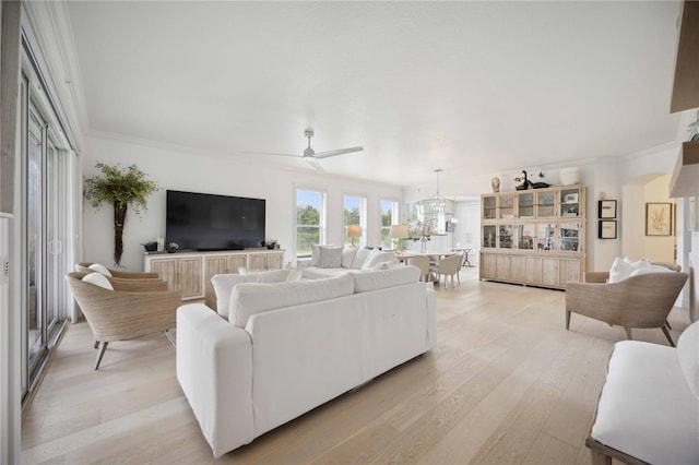 living room with ornamental molding, ceiling fan with notable chandelier, and light hardwood / wood-style flooring