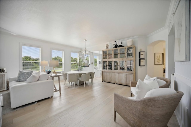 living room with crown molding, a notable chandelier, and light hardwood / wood-style flooring