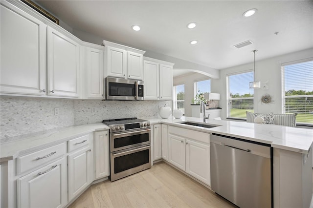 kitchen with white cabinetry, sink, light stone counters, kitchen peninsula, and stainless steel appliances