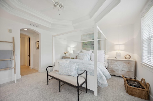 bedroom with ceiling fan, ornamental molding, a raised ceiling, and light colored carpet