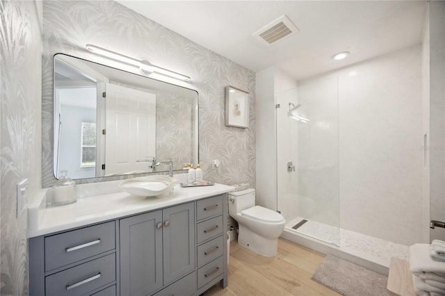 bathroom with vanity, wood-type flooring, toilet, and tiled shower