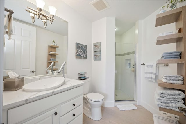 bathroom with toilet, a chandelier, vanity, a shower with door, and hardwood / wood-style flooring