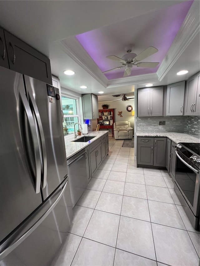 kitchen with sink, crown molding, light tile patterned floors, appliances with stainless steel finishes, and a raised ceiling