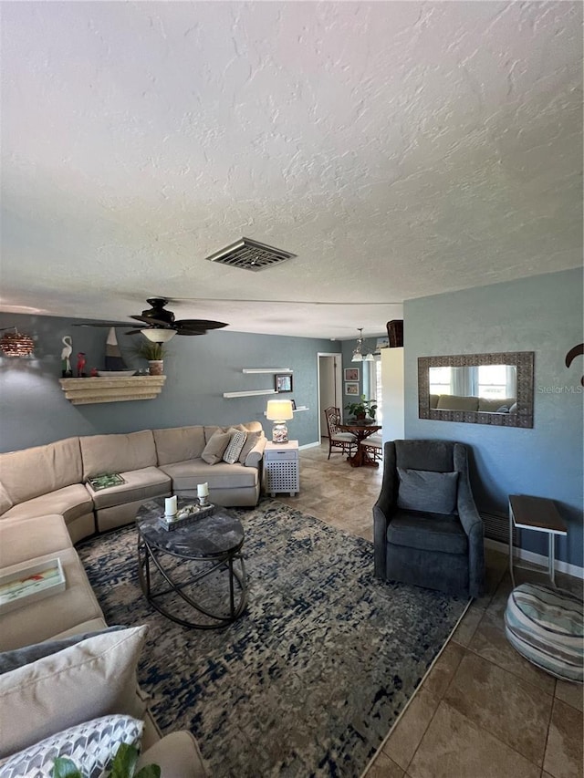 living room with ceiling fan and a textured ceiling