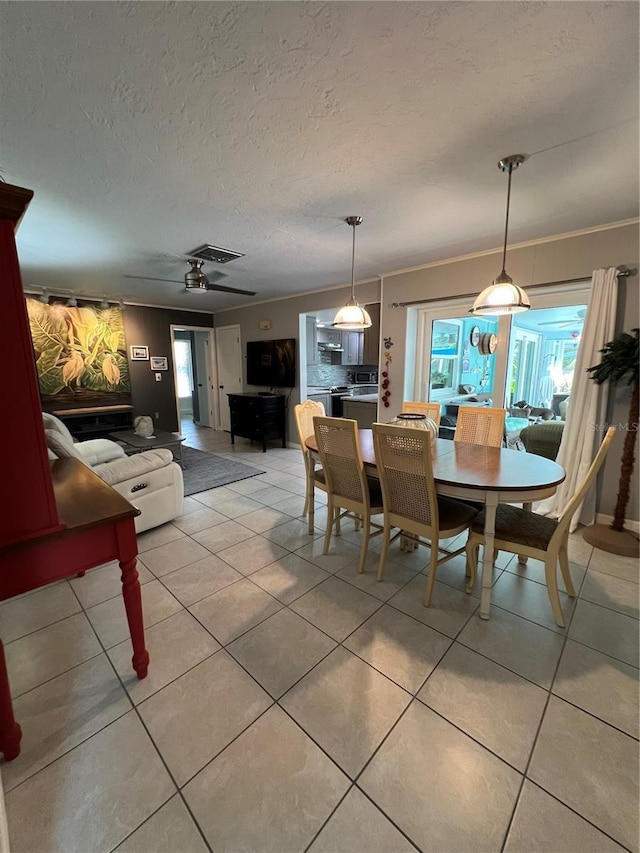 tiled dining space featuring crown molding, a wealth of natural light, ceiling fan, and a textured ceiling