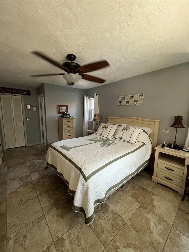 tiled bedroom featuring ceiling fan and a textured ceiling