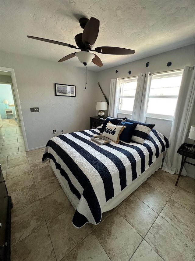 tiled bedroom featuring ceiling fan and a textured ceiling