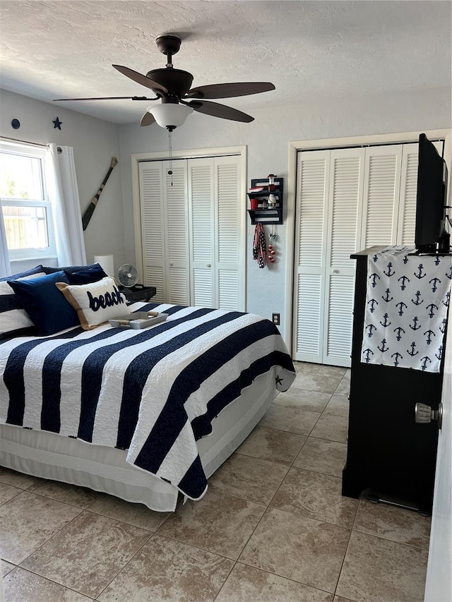 bedroom featuring ceiling fan, two closets, and a textured ceiling