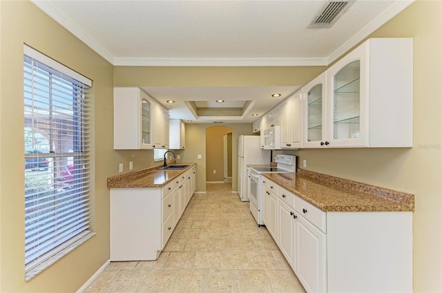 kitchen with sink, white cabinetry, dark stone countertops, a tray ceiling, and white appliances