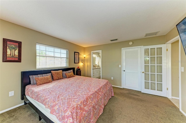 bedroom with carpet floors, a textured ceiling, and ensuite bath