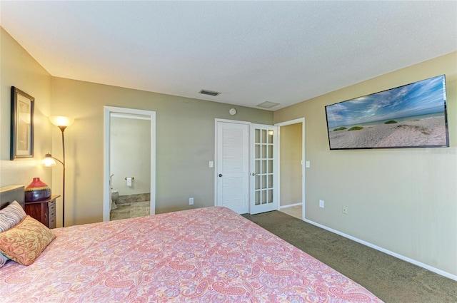 bedroom with french doors, ensuite bathroom, dark carpet, and a textured ceiling