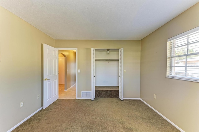 unfurnished bedroom featuring carpet, a textured ceiling, and a closet