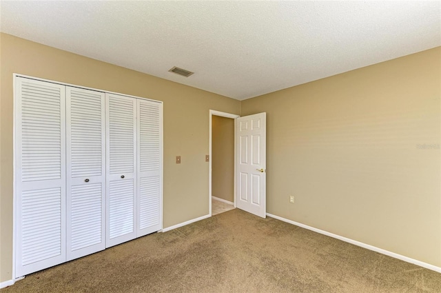 unfurnished bedroom featuring carpet floors, a closet, and a textured ceiling