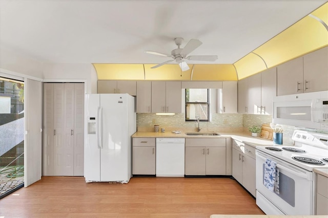 kitchen with tasteful backsplash, sink, white appliances, and light hardwood / wood-style floors