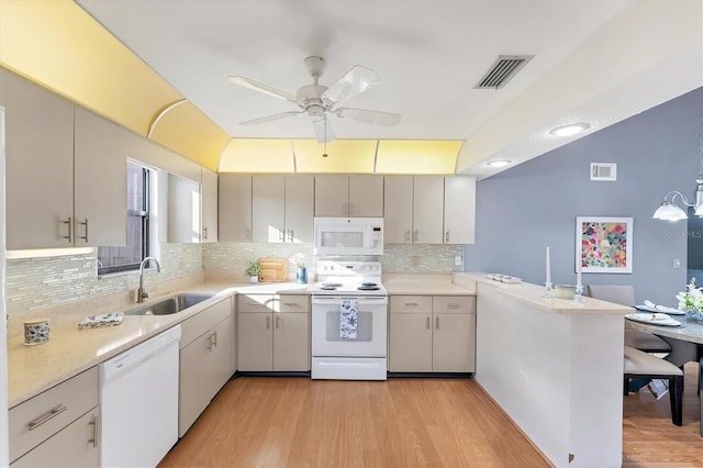 kitchen with sink, white appliances, decorative light fixtures, kitchen peninsula, and light wood-type flooring