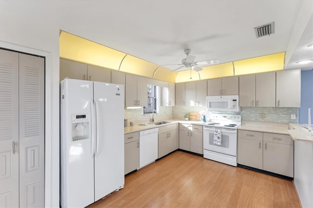 kitchen featuring tasteful backsplash, white appliances, light hardwood / wood-style floors, and sink