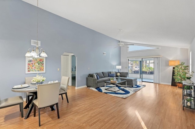 living room featuring high vaulted ceiling, ceiling fan with notable chandelier, and light hardwood / wood-style floors