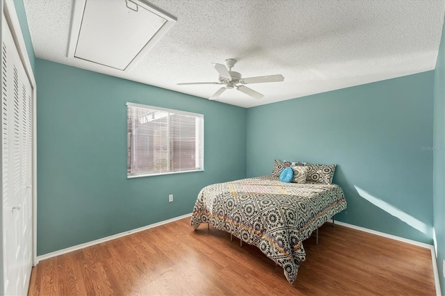 bedroom with hardwood / wood-style flooring, a textured ceiling, a closet, and ceiling fan