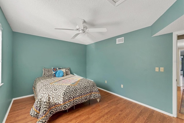 bedroom featuring wood-type flooring, ceiling fan, and a textured ceiling