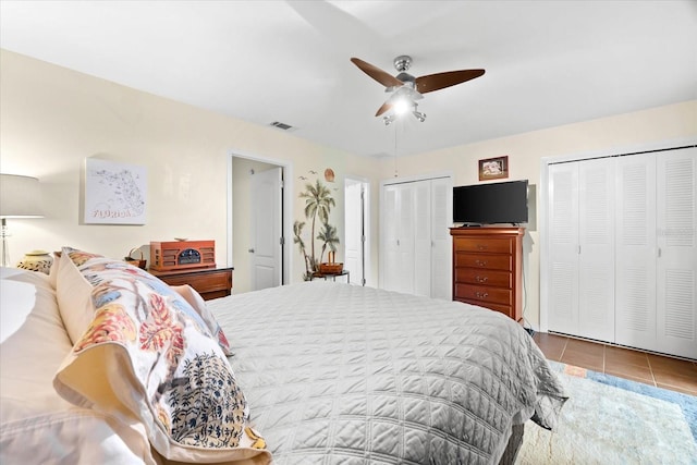 bedroom featuring two closets, tile patterned floors, and ceiling fan