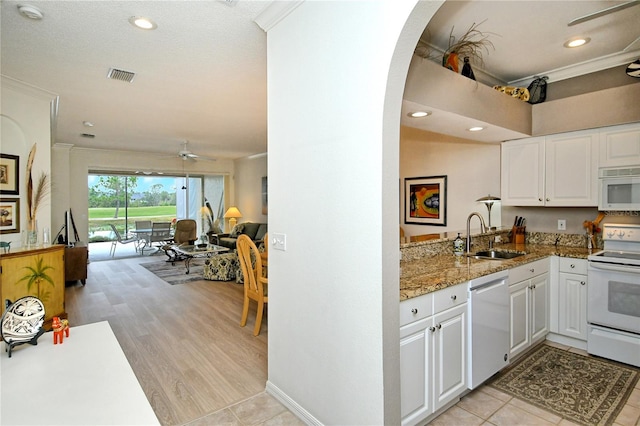 kitchen with light stone counters, white appliances, sink, and white cabinets