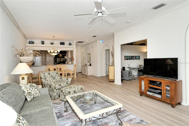 living room with ornamental molding, ceiling fan with notable chandelier, a textured ceiling, and light wood-type flooring