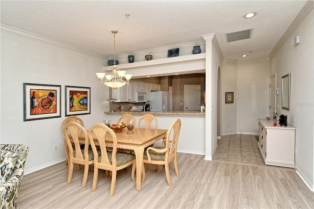 dining area featuring ornamental molding, a notable chandelier, and light hardwood / wood-style floors