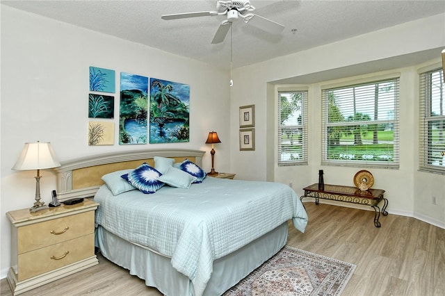 bedroom featuring ceiling fan, a textured ceiling, and light wood-type flooring