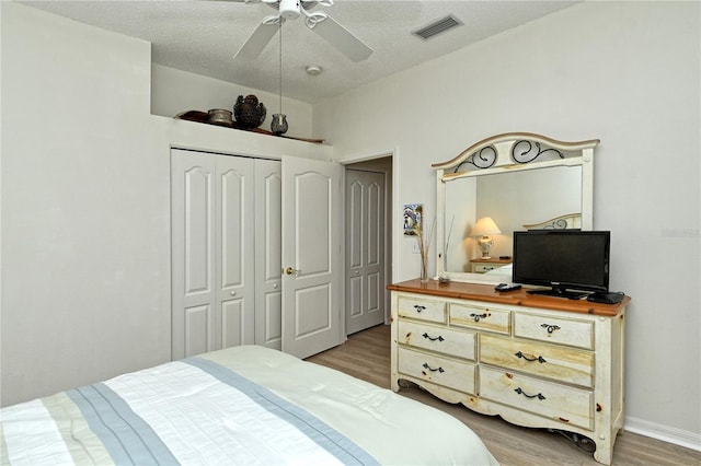 bedroom featuring ceiling fan, a textured ceiling, light hardwood / wood-style floors, and a closet