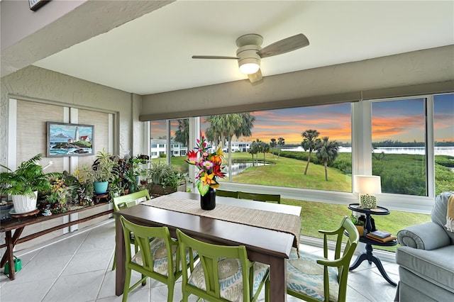 sunroom / solarium featuring a water view and ceiling fan