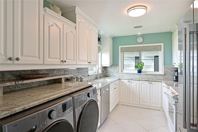 clothes washing area featuring sink, light tile patterned floors, and washer and clothes dryer