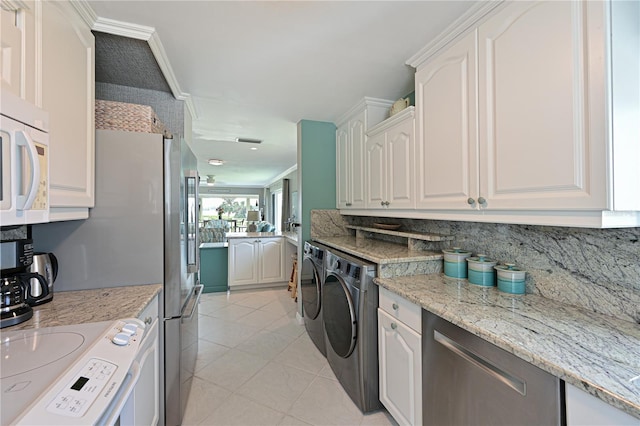 laundry area featuring light tile patterned floors, ornamental molding, and washing machine and clothes dryer