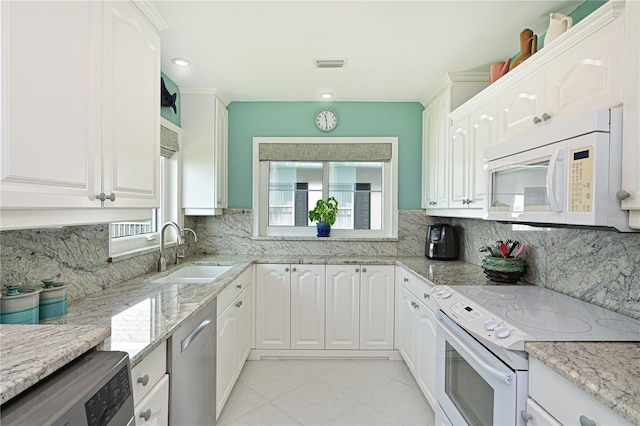 kitchen with white appliances, white cabinets, and a sink