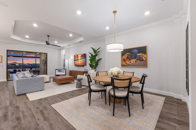 dining room featuring ceiling fan, ornamental molding, a tray ceiling, and hardwood / wood-style floors