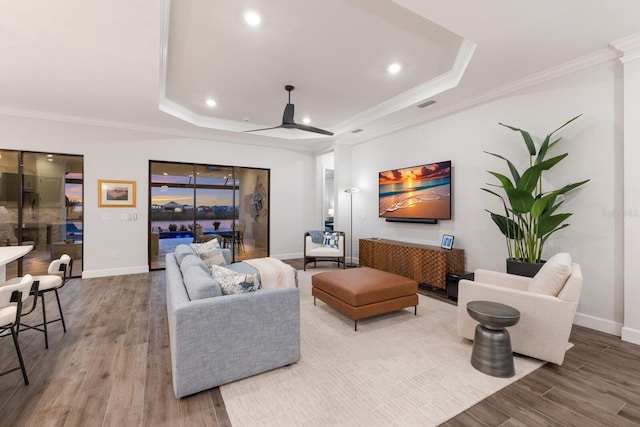 living room featuring crown molding, a raised ceiling, and hardwood / wood-style floors