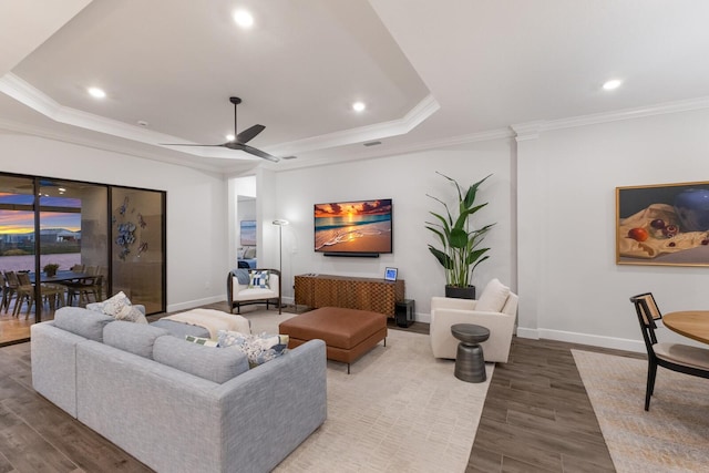 living room with hardwood / wood-style flooring, ornamental molding, and a raised ceiling