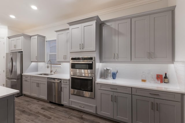 kitchen featuring sink, gray cabinetry, crown molding, tasteful backsplash, and appliances with stainless steel finishes