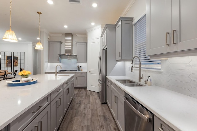 kitchen featuring gray cabinets, sink, hanging light fixtures, stainless steel appliances, and wall chimney range hood